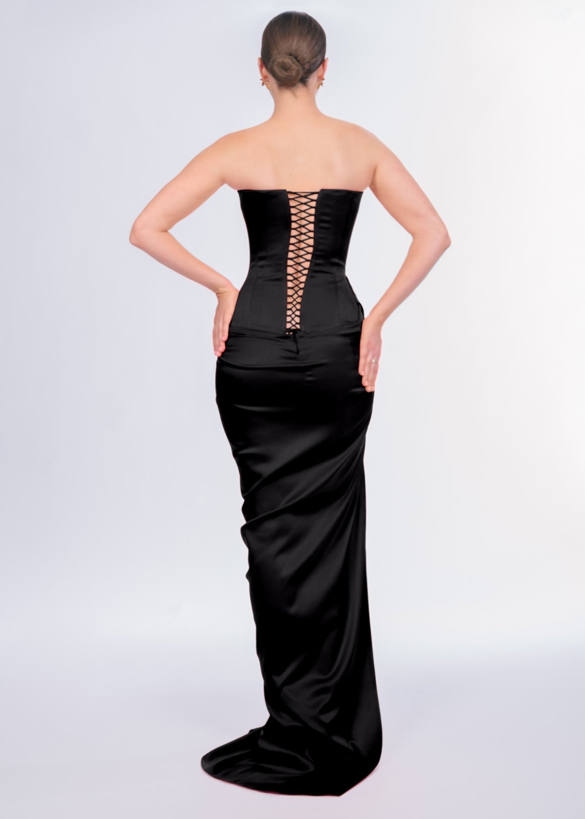 Black strapless gown with lace-up back on a white background
